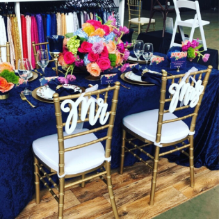 Gold chairs and navy table setting with colorful flowers for a formal event