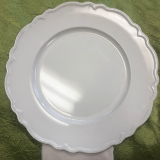 White scalloped ceramic plate on a green fabric background