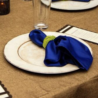 White plate with a folded blue napkin on a brown table setting