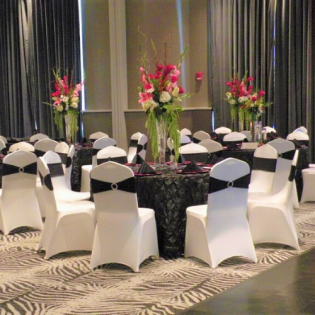 Round banquet tables with black-and-white chair covers and pink floral centerpieces in a decorated event hall