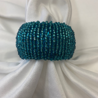 Teal beaded ring on white fabric folds