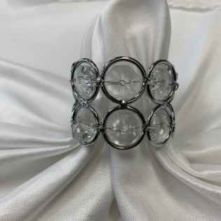 Silver circular bracelet on white draped fabric background