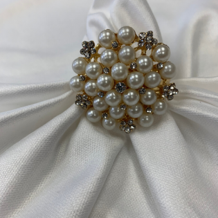 Pearl and gold floral brooch on white draped fabric