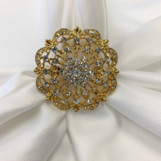 Gold floral jeweled brooch on white draped fabric, centered like a decorative fastener