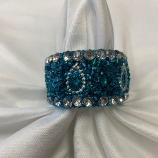 Teal and silver jeweled bracelet with teardrop designs on white satin background