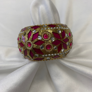 Red and gold jeweled bracelet with floral designs on white fabric