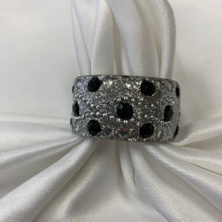 Silver glittery napkin ring with black polka dots on a white cloth napkin