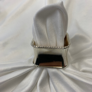 White folded napkin in a silver napkin ring on a white tablecloth