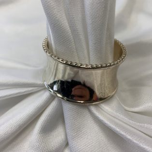 Silver ring with a beaded edge on white draped fabric
