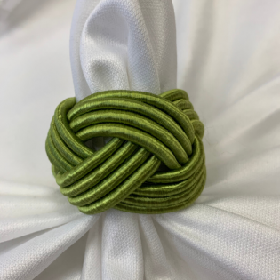 Green braided fabric knot on white folded fabric background
