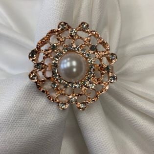 Pearl-centered floral brooch with gold and clear stones on white fabric