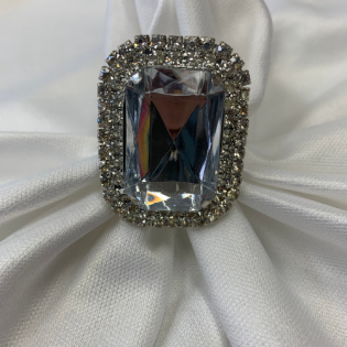 Rectangular clear gemstone ring with a silver halo on white satin fabric