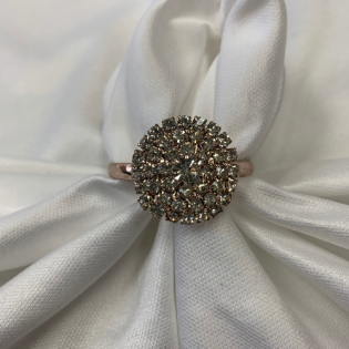 Silver ring with a round cluster of sparkling stones on white fabric