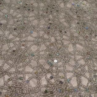 Close-up of beige lace fabric with a floral circular pattern and small iridescent beads