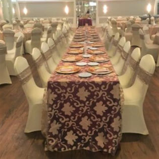 Long banquet tables with patterned tablecloths and plates in a decorated event hall