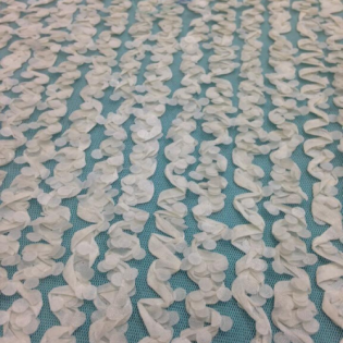 Rows of white crocheted flowers on a teal fabric background