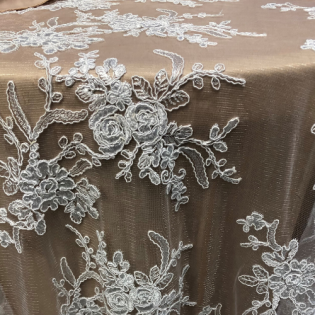 White lace floral embroidery on beige fabric with a sheer, elegant texture