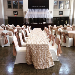 Elegant banquet hall with a long white-draped table and chairs arranged in rows for an event
