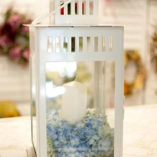 White decorative lantern with blue flowers inside on a bright table.