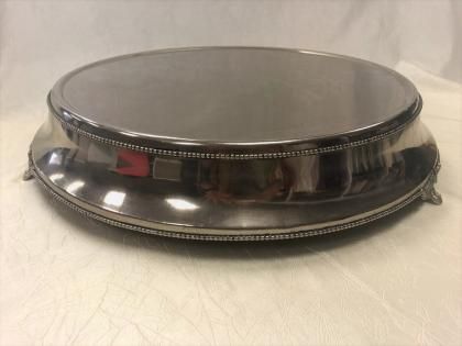 Polished silver metal bowl or tray with a reflective surface, viewed from the side on a light background