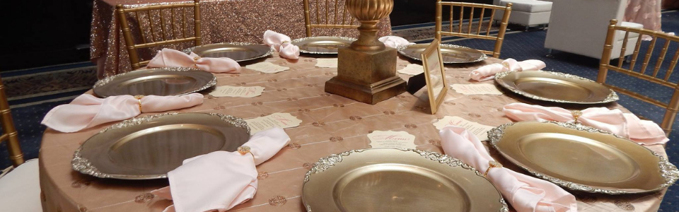 Dining table set with plates, folded napkins, and a centerpiece in a softly lit banquet room