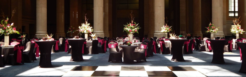 Elegant banquet hall with round tables, burgundy chairs, and floral centerpieces in warm light