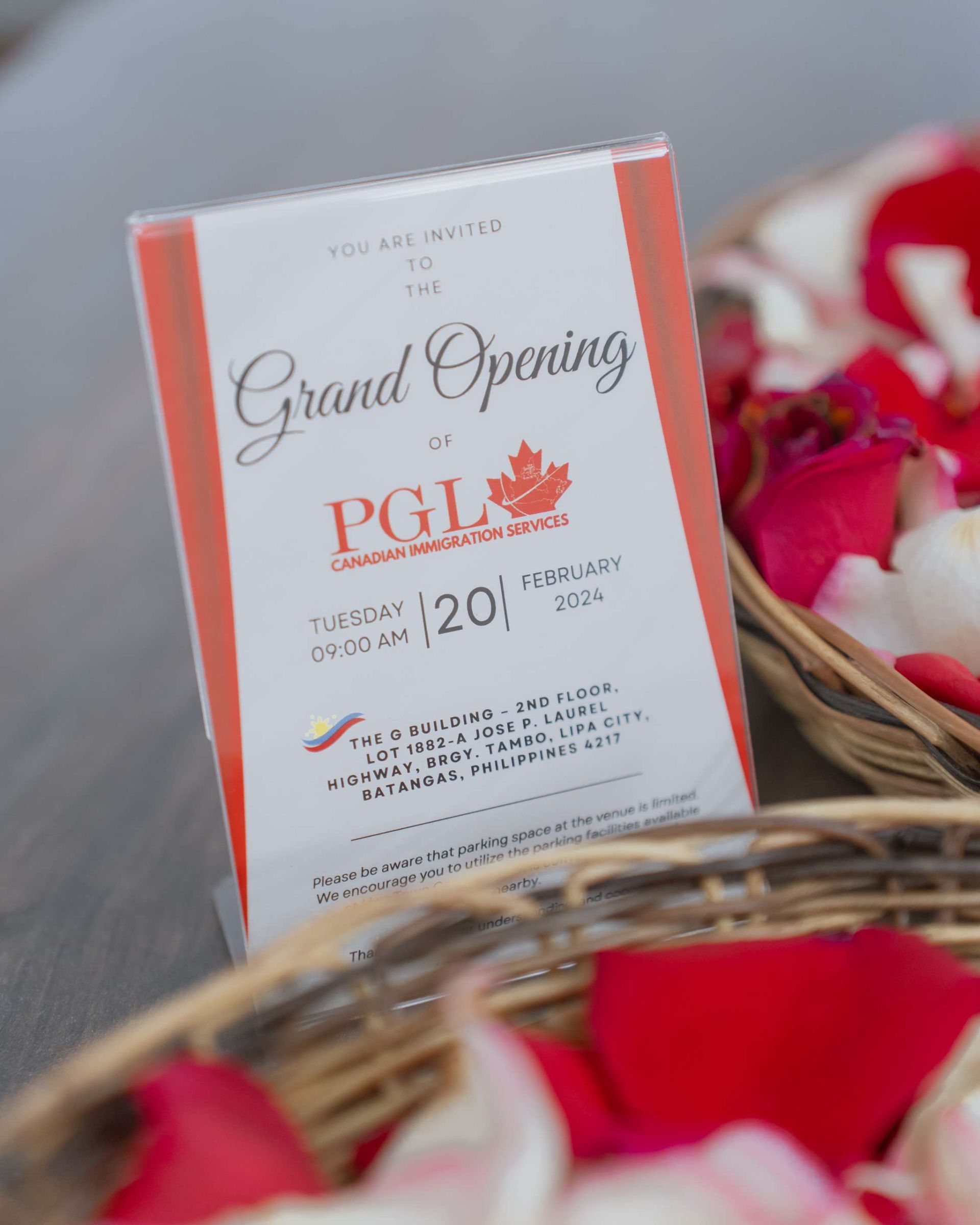A flyer for a grand opening of pgl is in a basket of rose petals