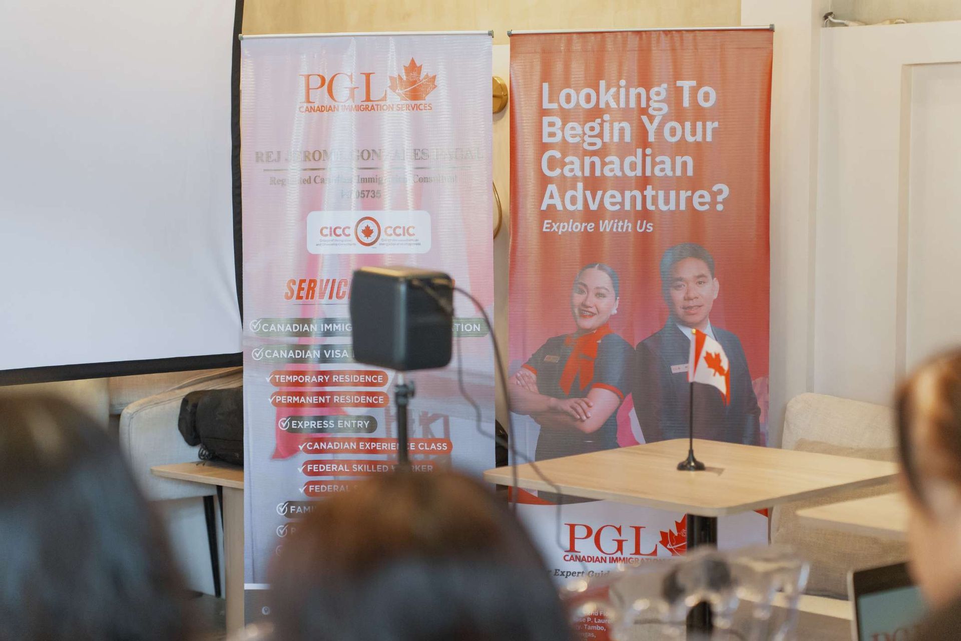 A group of people are sitting in front of a sign that says `` looking to begin your canadian adventure ? ''