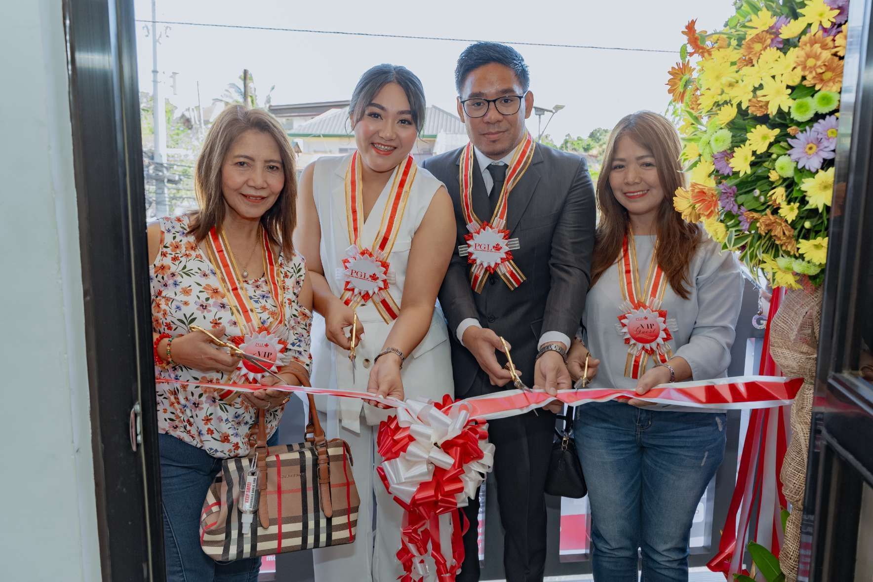 A group of people are cutting a red and white ribbon.