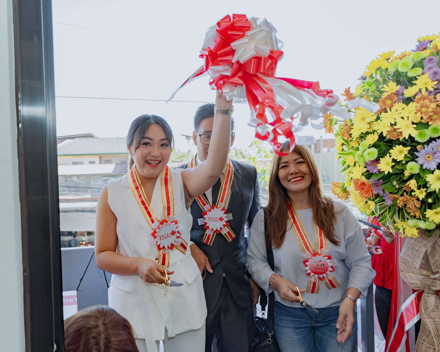 A group of people are standing next to each other holding a red and white bow.