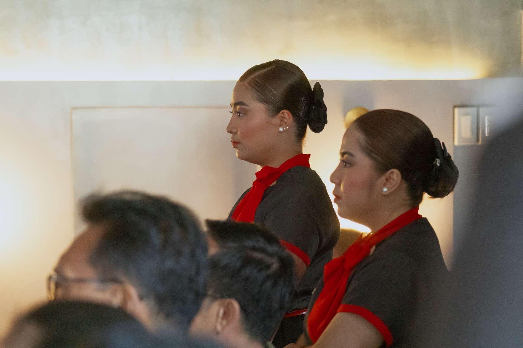 A group of people are sitting in a room and two women are standing next to each other
