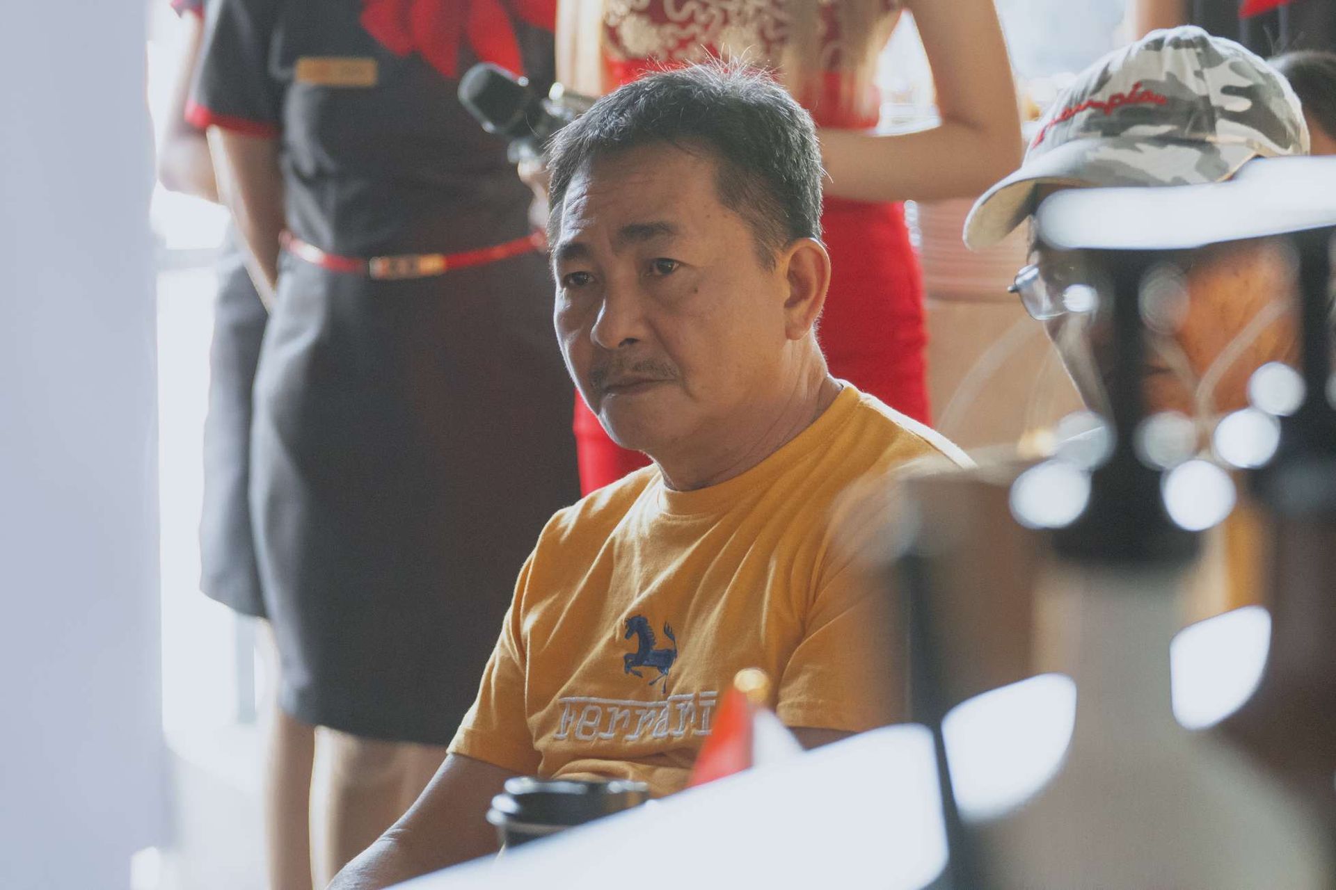 A man in a yellow shirt is sitting at a table.