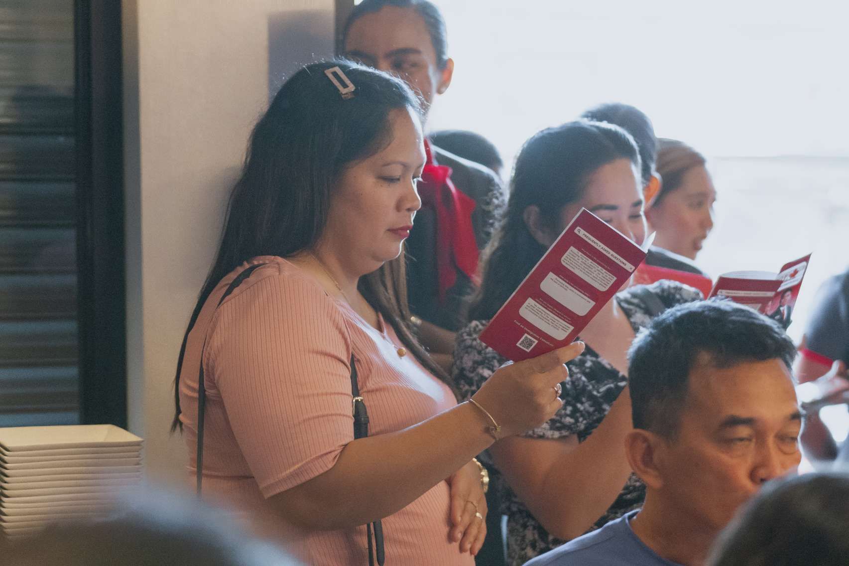 A woman is reading a book in a crowd of people.