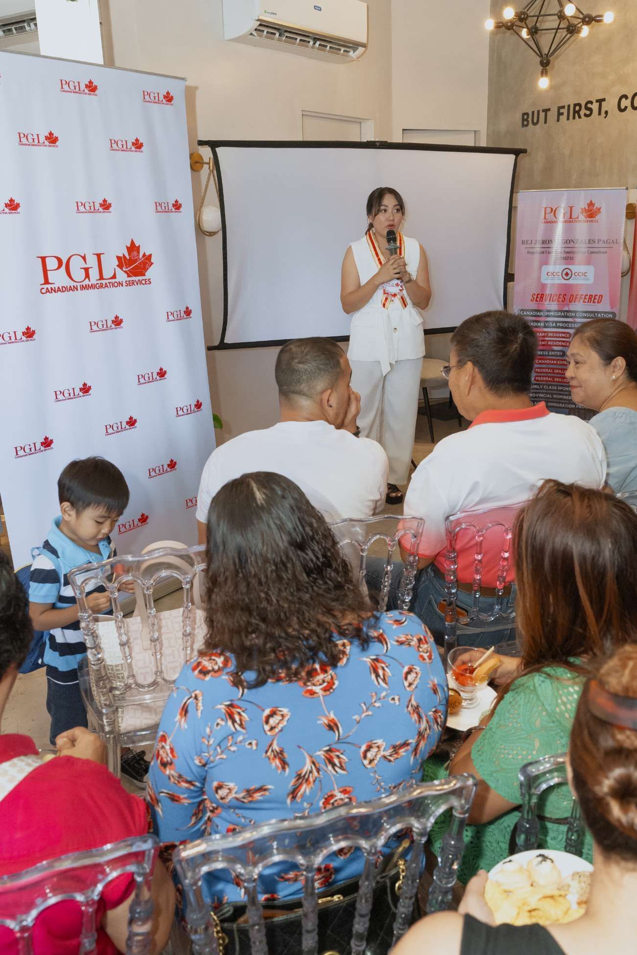 A woman is giving a presentation to a group of people sitting at tables.
