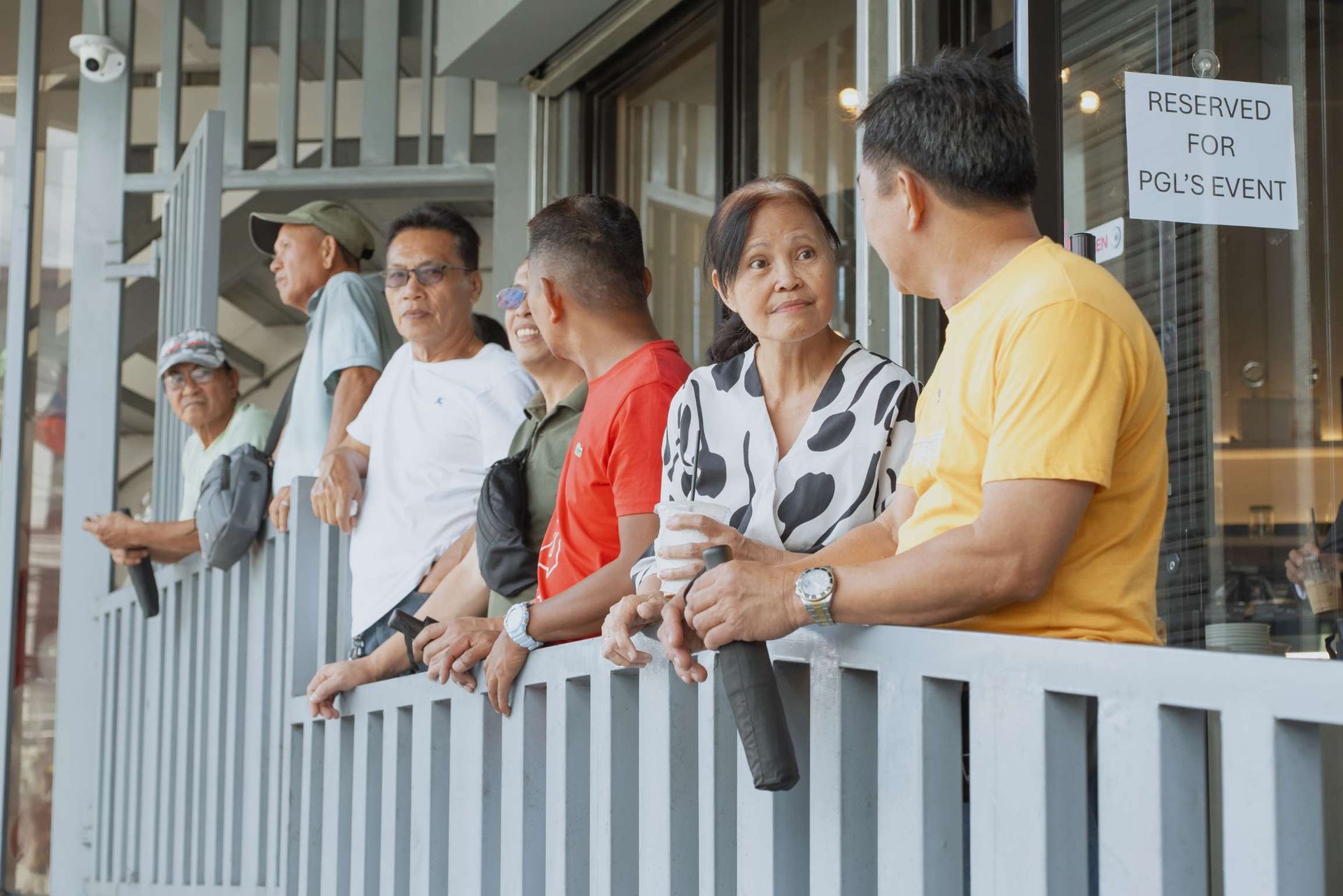 A group of people are standing on a balcony looking out a window.