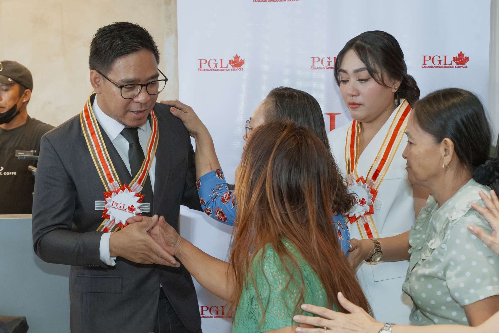 A group of people are standing around a man in a suit and tie.