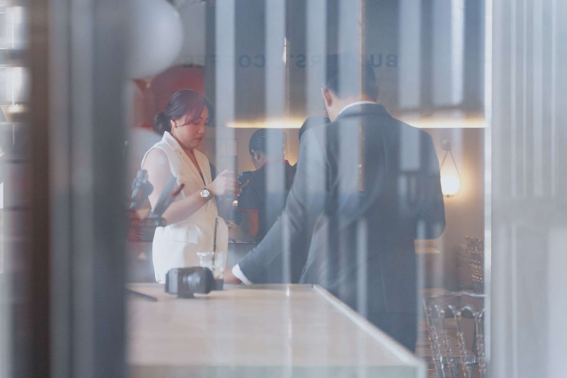 A man in a suit and a woman in a white coat are standing in a restaurant.