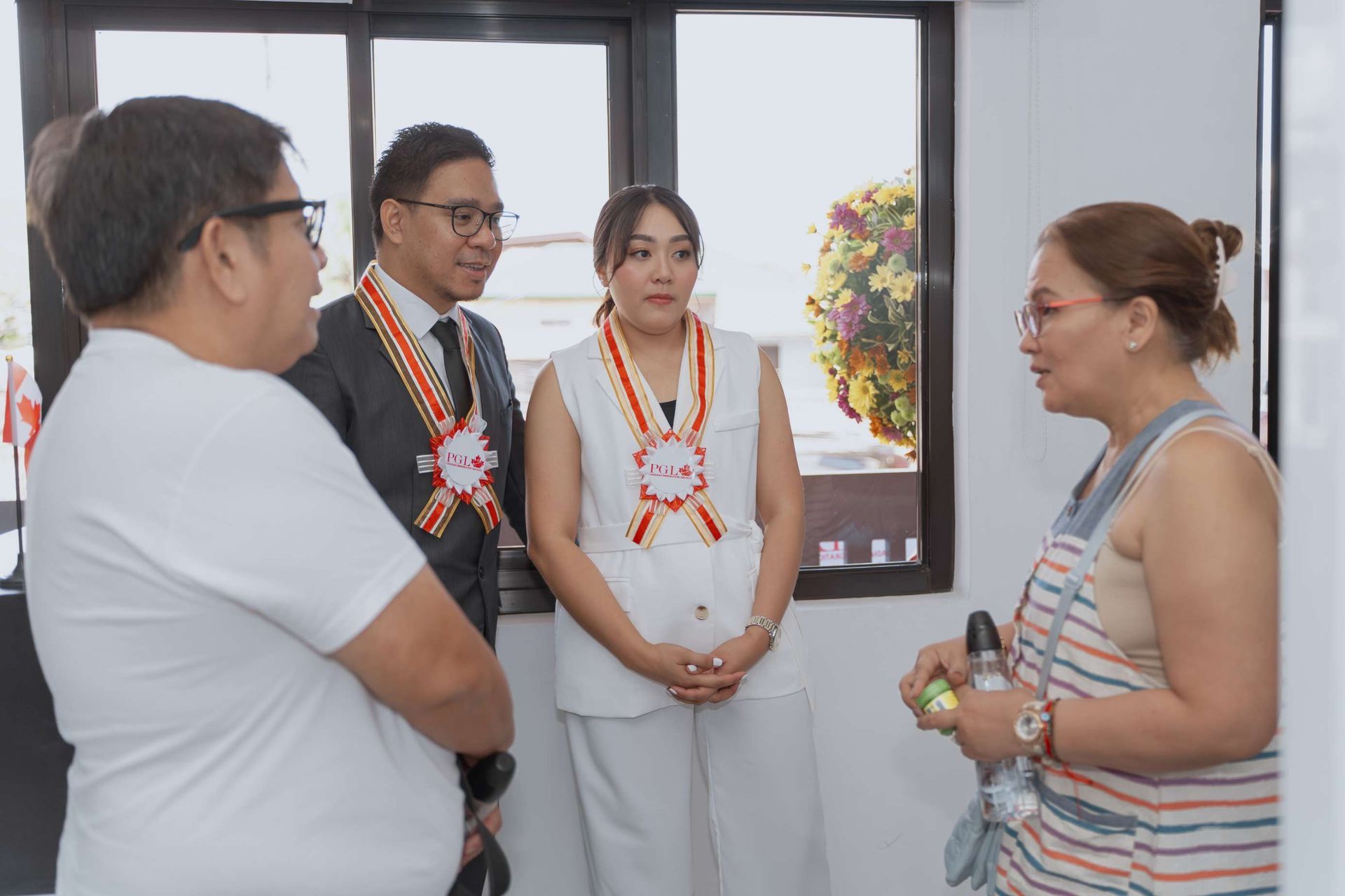 A group of people are standing in a room talking to each other.