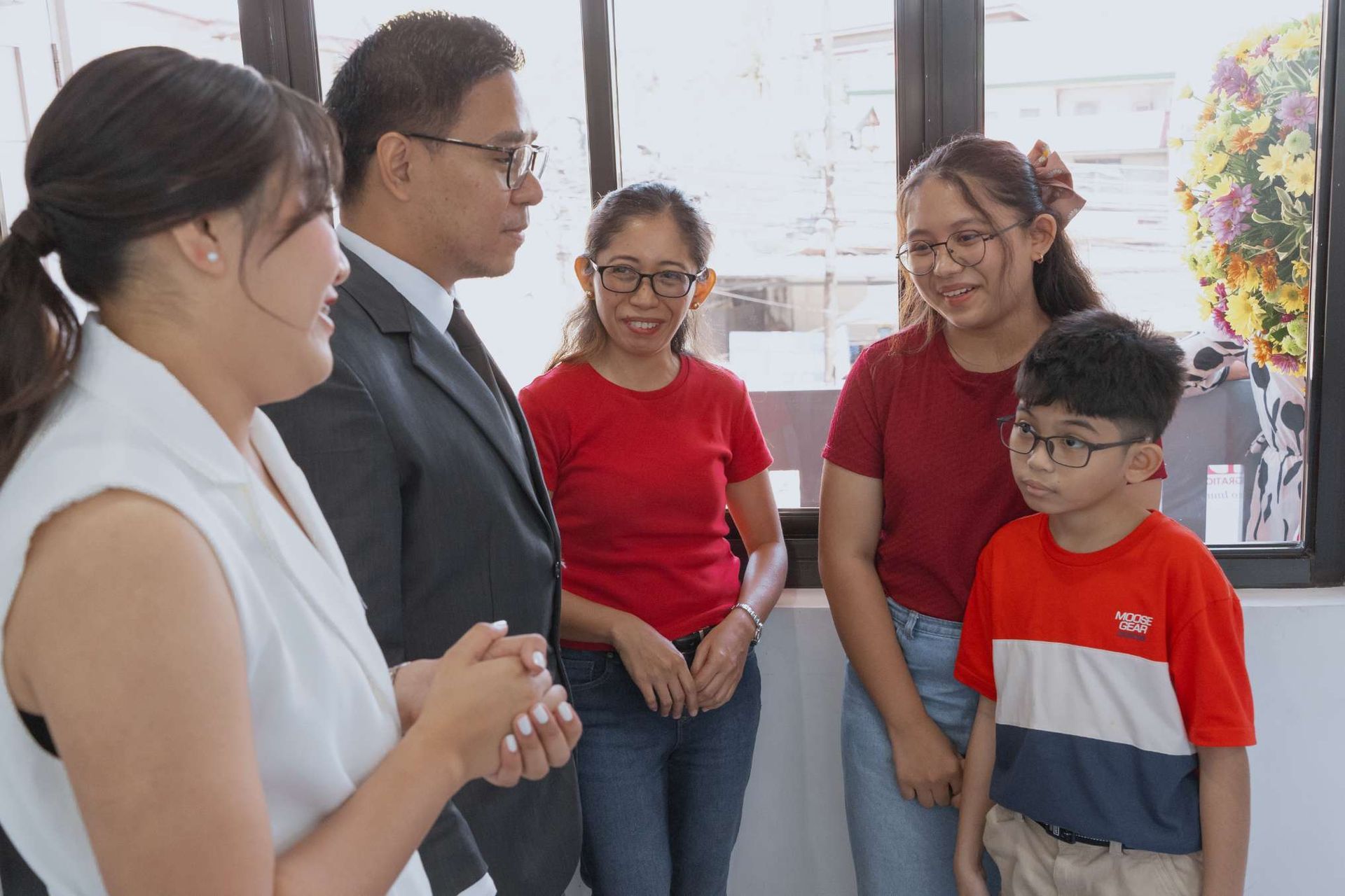 A group of people are standing next to each other in front of a window.