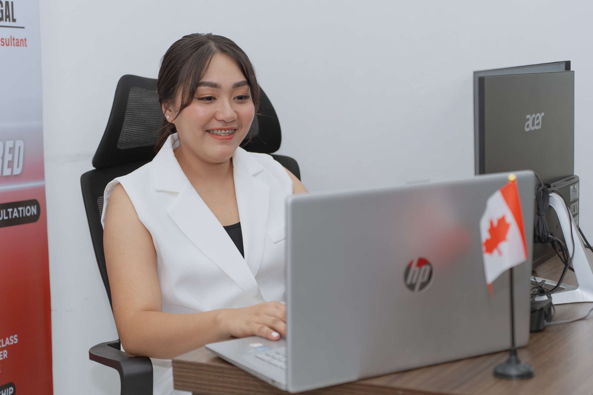 A woman is sitting at a desk using a laptop computer.