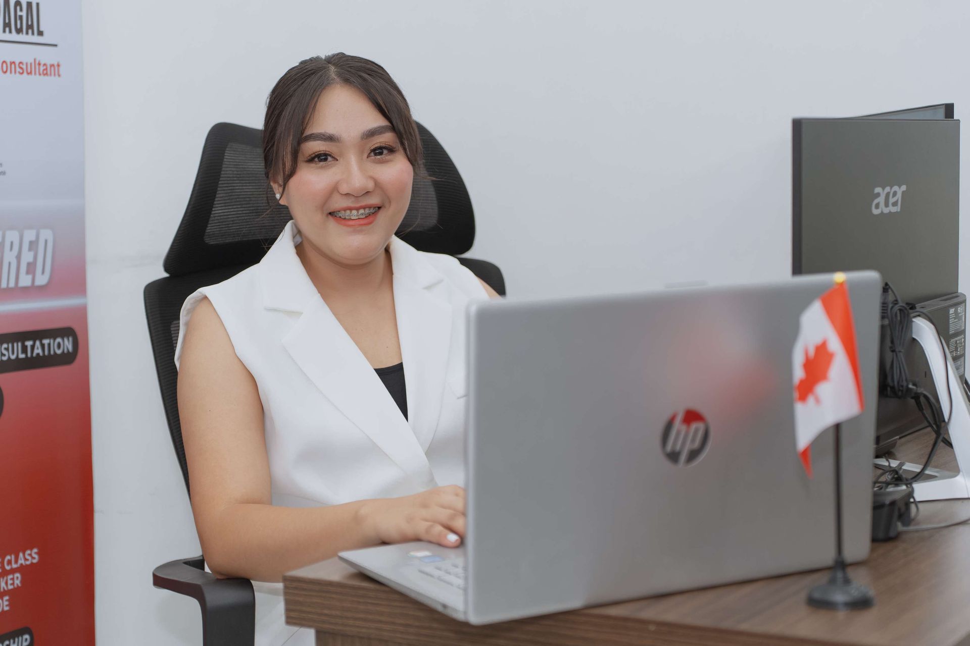 A woman is sitting at a desk in front of a laptop computer.