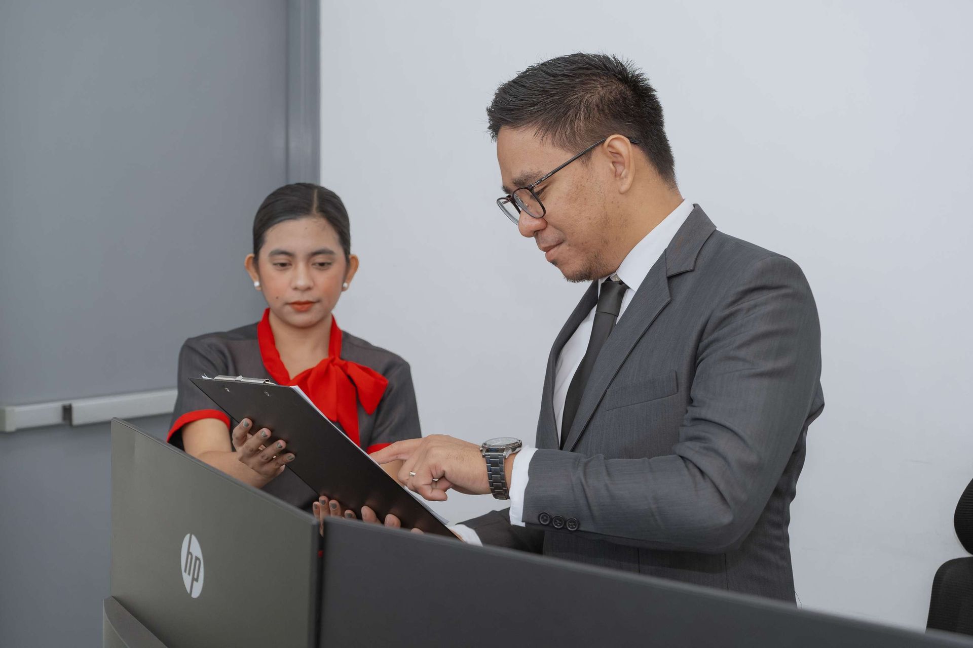 A man and a woman are standing at a podium looking at a clipboard.