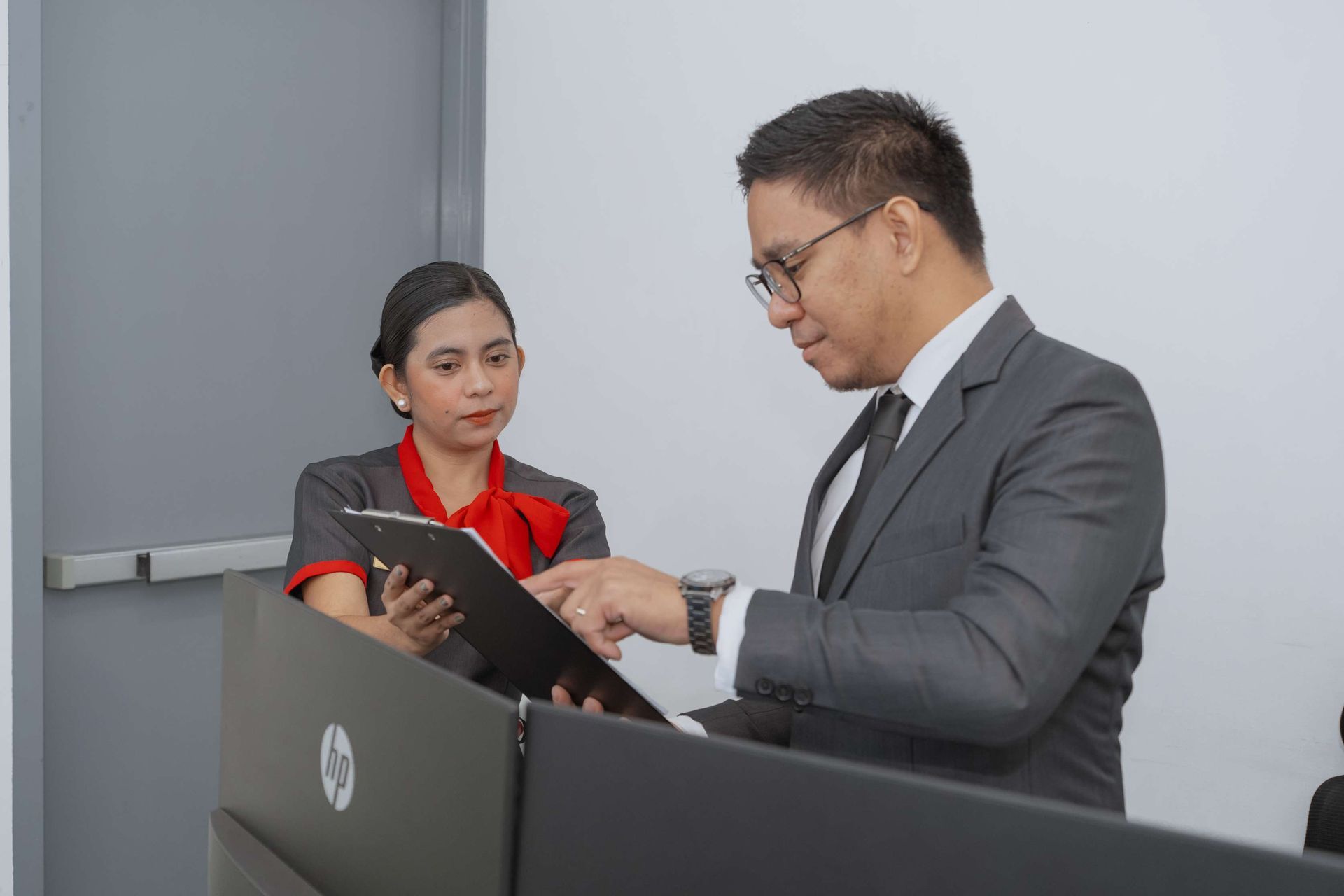 A man and a woman are standing at a podium looking at a tablet.