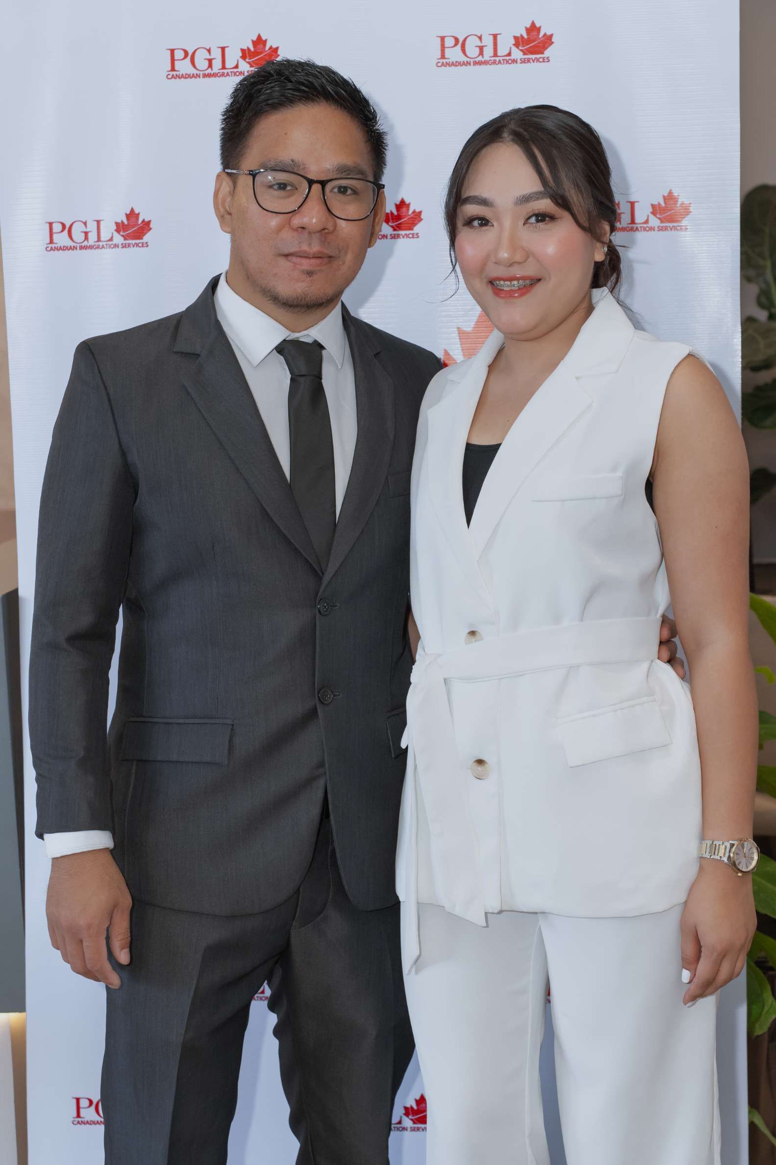 A man in a suit and tie stands next to a woman in a white vest