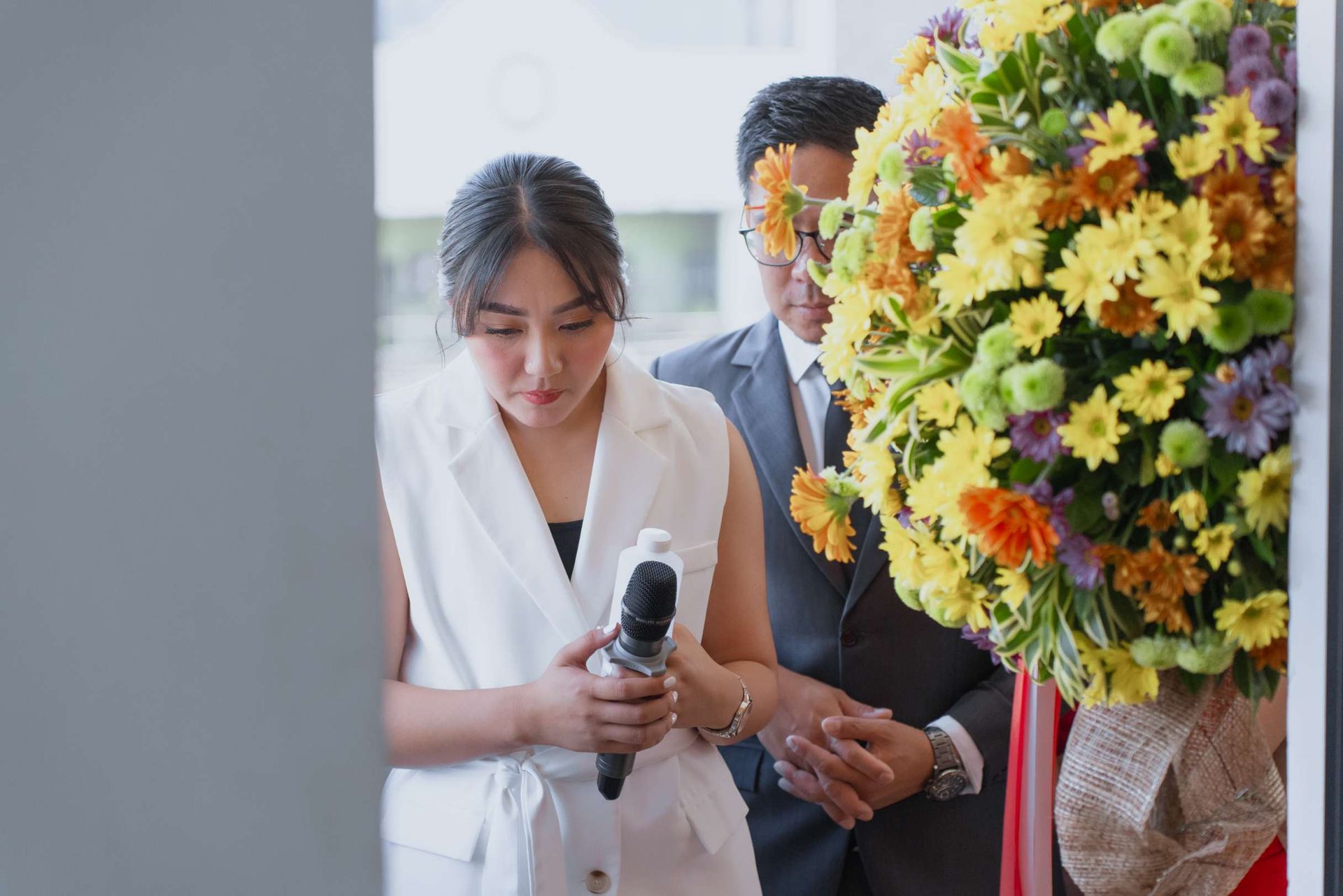 A man and a woman are standing next to a bouquet of flowers.