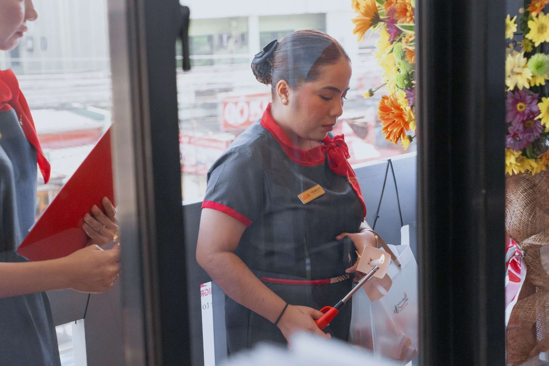 A woman is standing in front of a window holding a pair of scissors.