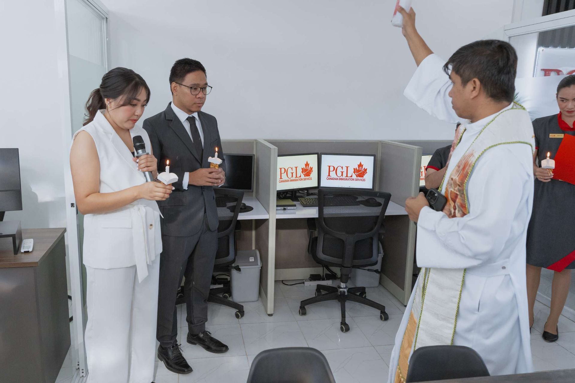 A man in a white robe is standing in front of a cubicle with a computer on it.