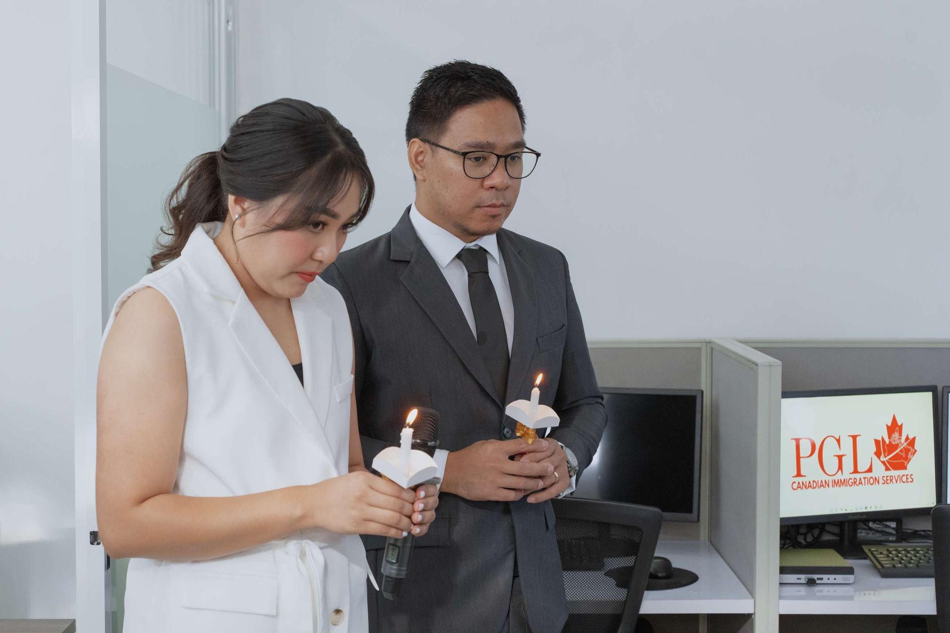 A man and a woman are holding candles in an office cubicle.