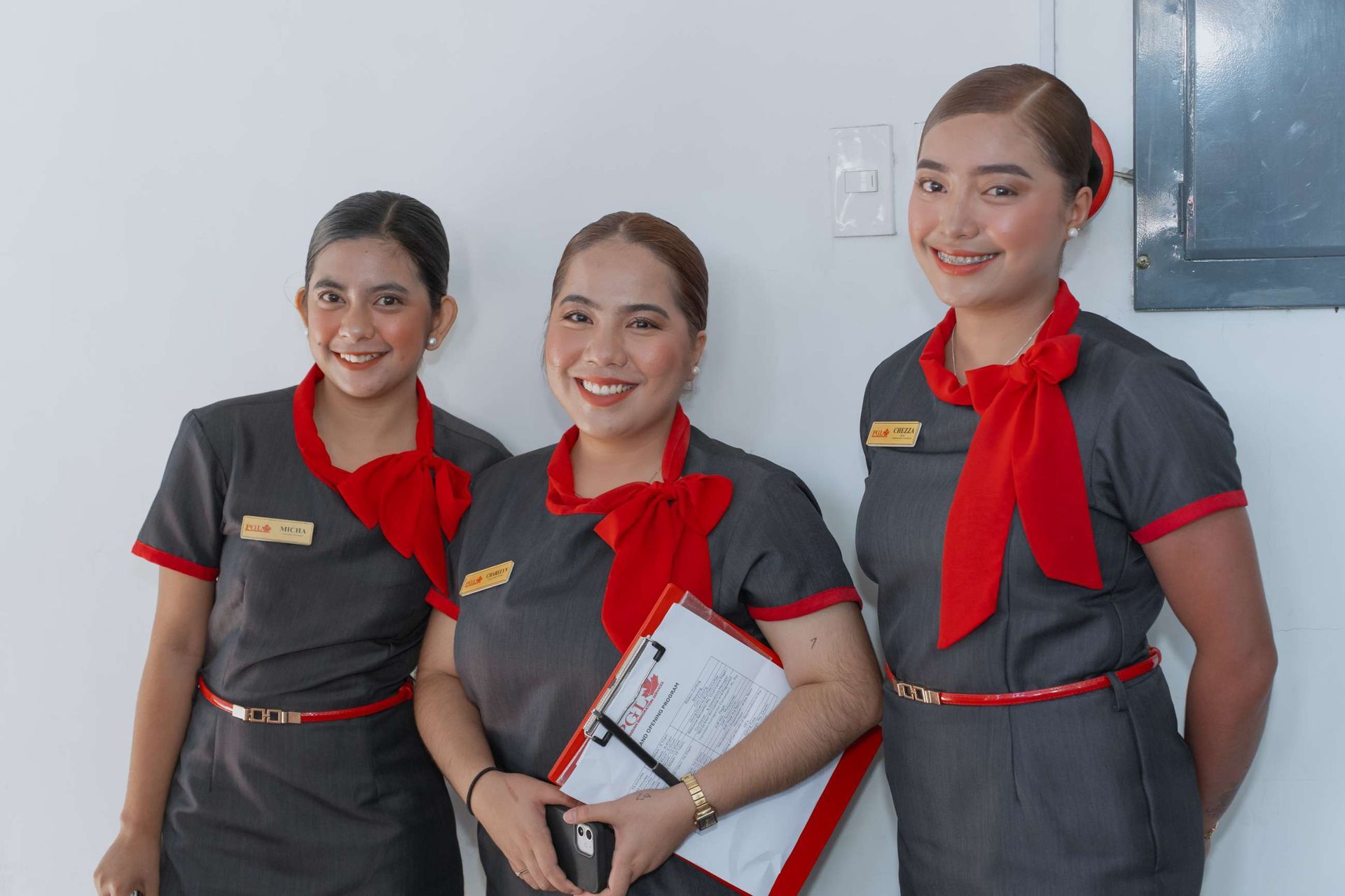 Three women in uniforms are standing next to each other and smiling.