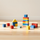 Bloques de madera de colores dispuestos sobre una mesa, que incluyen una pequeña torre, una forma de casa y cubos dispersos.